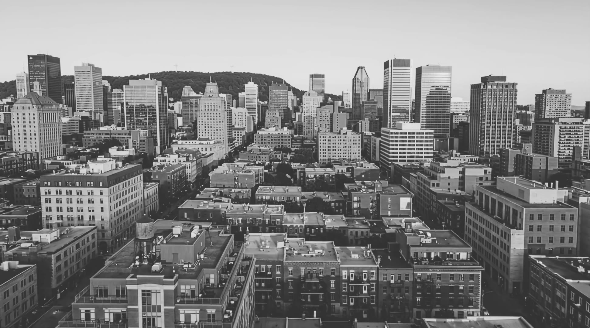 Aerial black-and-white view of the Montreal skyline at dusk.